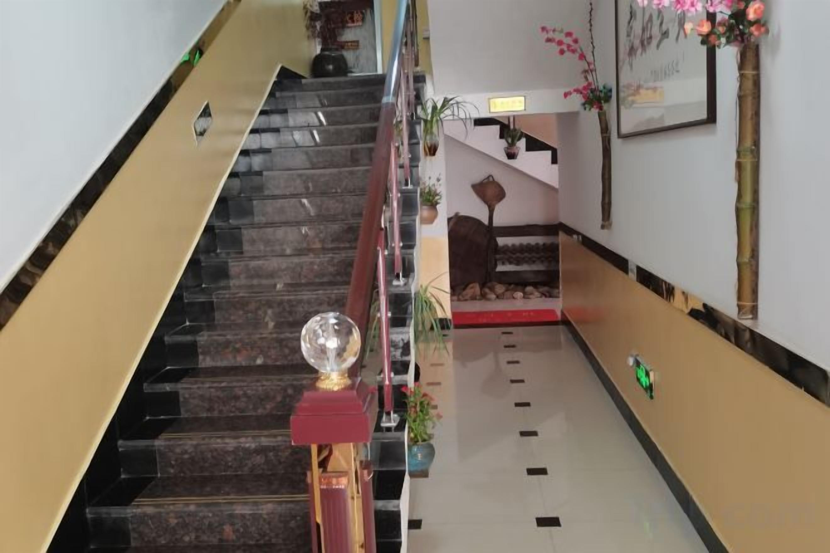 Una escalera de hotel con barandilla roja, una esfera decorativa y un objeto verde en el suelo.