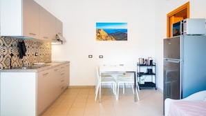 Une cuisine compacte comprenant un coin repas, un réfrigérateur et un climatiseur fixé au mur.