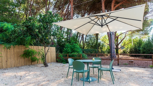Une terrasse extérieure avec une table et des chaises, entourée d’une clôture en bois et d’arbres.