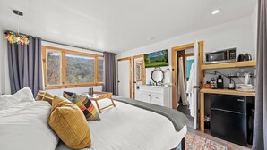 Un dormitorio con una cama grande, una mesita de noche, un aparador, un microondas y un refrigerador.