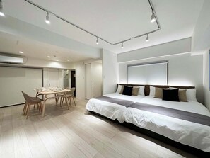 Una habitación de hotel moderna con una cama grande, una mesa de comedor con sillas y un rincón de comedor aparte.