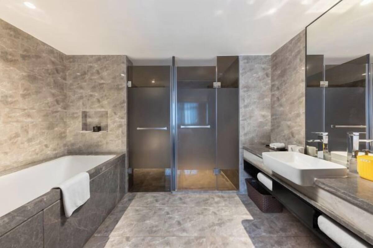 A modern bathroom with a bathtub, a walk-in shower, and a vanity with a mirror.