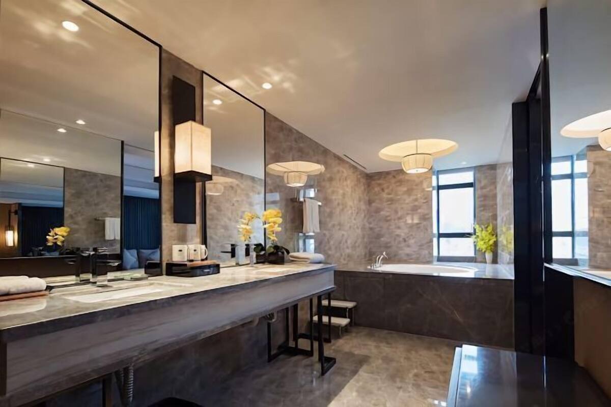 A modern bathroom with a large mirror, a vanity with a sink, and pendant lighting.