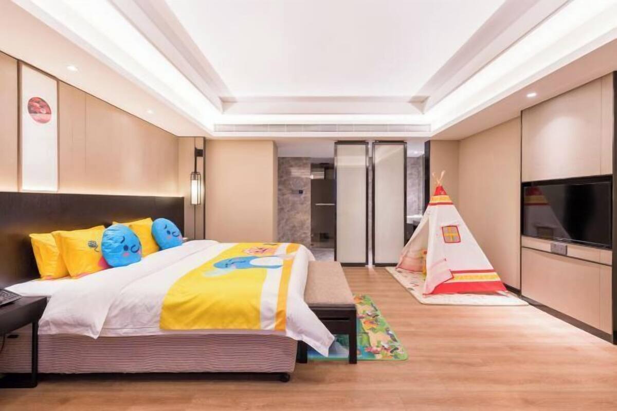 A hotel room with a bed, a TV, a kitchenette, and a tent-like structure.