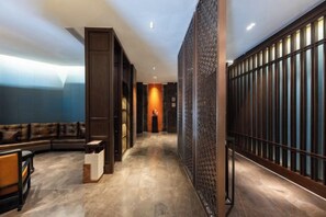 A hotel corridor with a curved seating area, a patterned wall, and a person standing at the end. - Yue Hotel (Fuzhou)