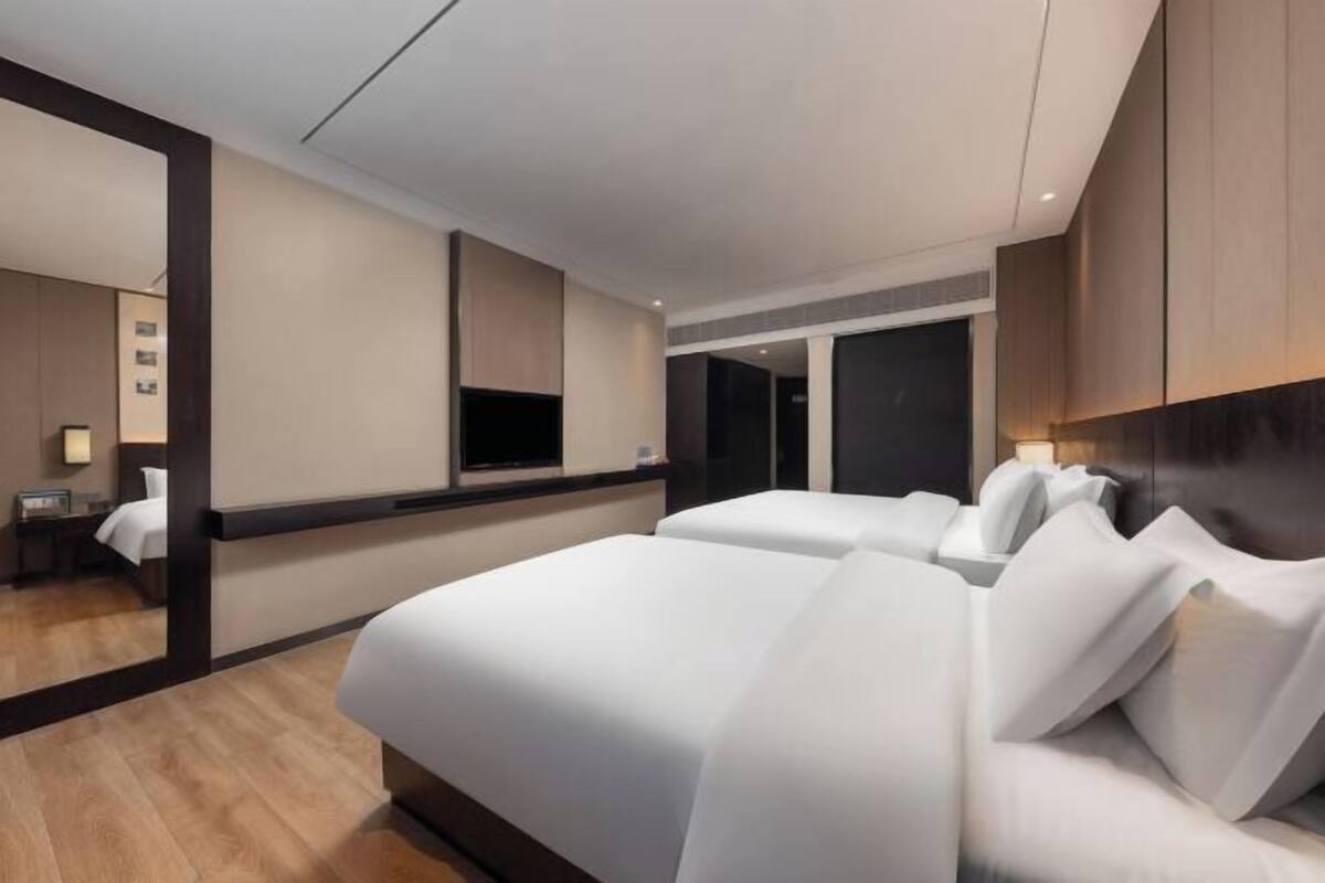 A hotel room with a large bed, a desk, a chair, and a TV.