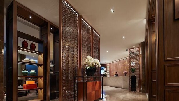 A lobby with a reception desk, decorative panels, and a display of vases. - Yue Hotel (Fuzhou)