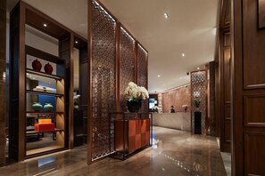 A lobby with a reception desk, decorative panels, and a display of vases. - Yue Hotel (Fuzhou)