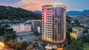 A multi-story hotel with a curved facade, surrounded by residential buildings and a hilly landscape. - Yue Hotel (Fuzhou)