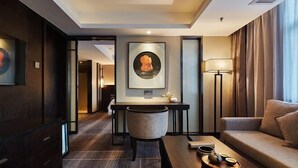 A modern hotel room with a dark wood desk, a comfortable sofa, and a framed artwork on the wall. - Yue Hotel (Fuzhou)