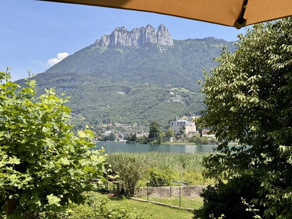 A mountainous landscape with a castle-like building and a lake. - La Baie des Voiles Studio 108 (Duingt)