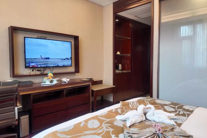 A hotel room with a bed, a desk, a television, and a wardrobe.