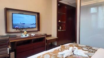 A hotel room with a bed, a desk, a television, and a wardrobe.