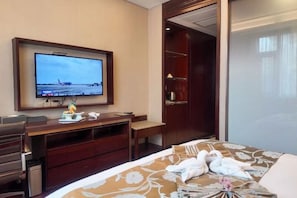 Une chambre d’hôtel équipée d’un lit, d’un bureau, d’une télévision et d’une armoire.