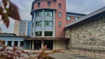 A building with a curved facade, a central entrance, and a decorative wall with intricate designs.