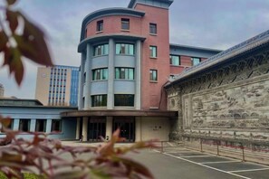A building with a curved facade, a central entrance, and a decorative wall with intricate designs. - Ningwozhuang Hotel (Building 1) (Lanzhou)