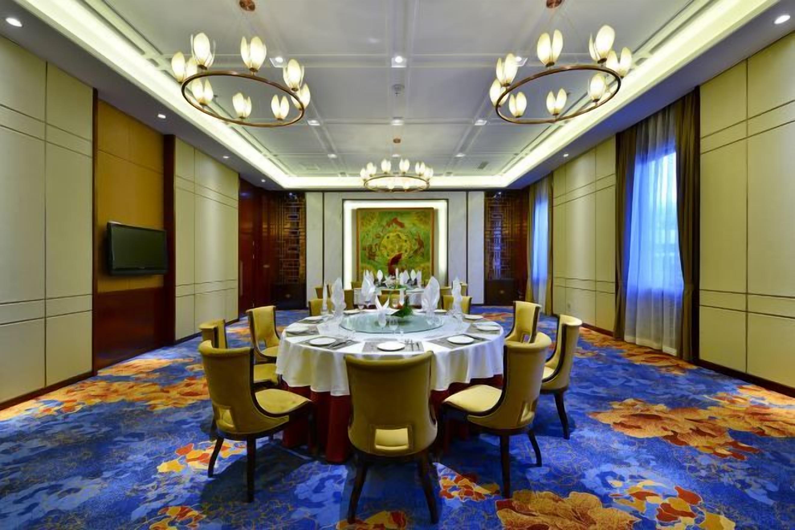 A conference room with a round table, chairs, and a chandelier.