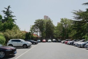 A parking lot with multiple cars parked in rows, surrounded by trees and buildings in the background. - Ningwozhuang Hotel (Building 1) (Lanzhou)