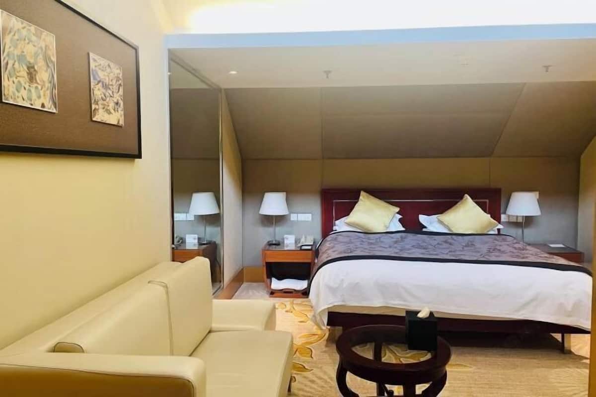 A hotel room with a bed, a sofa, a small table, and a nightstand.