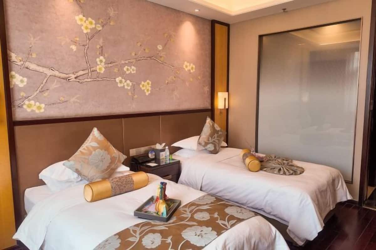 A hotel room with two beds, a large wall mural, a nightstand, and a sliding door.
