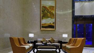 A lobby with a large painting, two sofas, a coffee table, and a floor lamp.