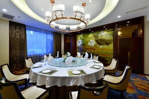 A round dining table with white tablecloth and gold accents, surrounded by chairs with cushioned seats. - Ningwozhuang Hotel (Building 1) (Lanzhou)