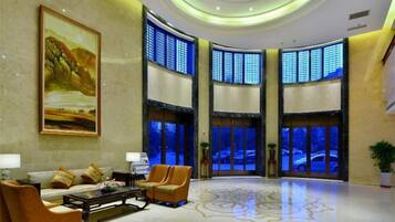 A lobby with a large painting, seating area, and large windows.