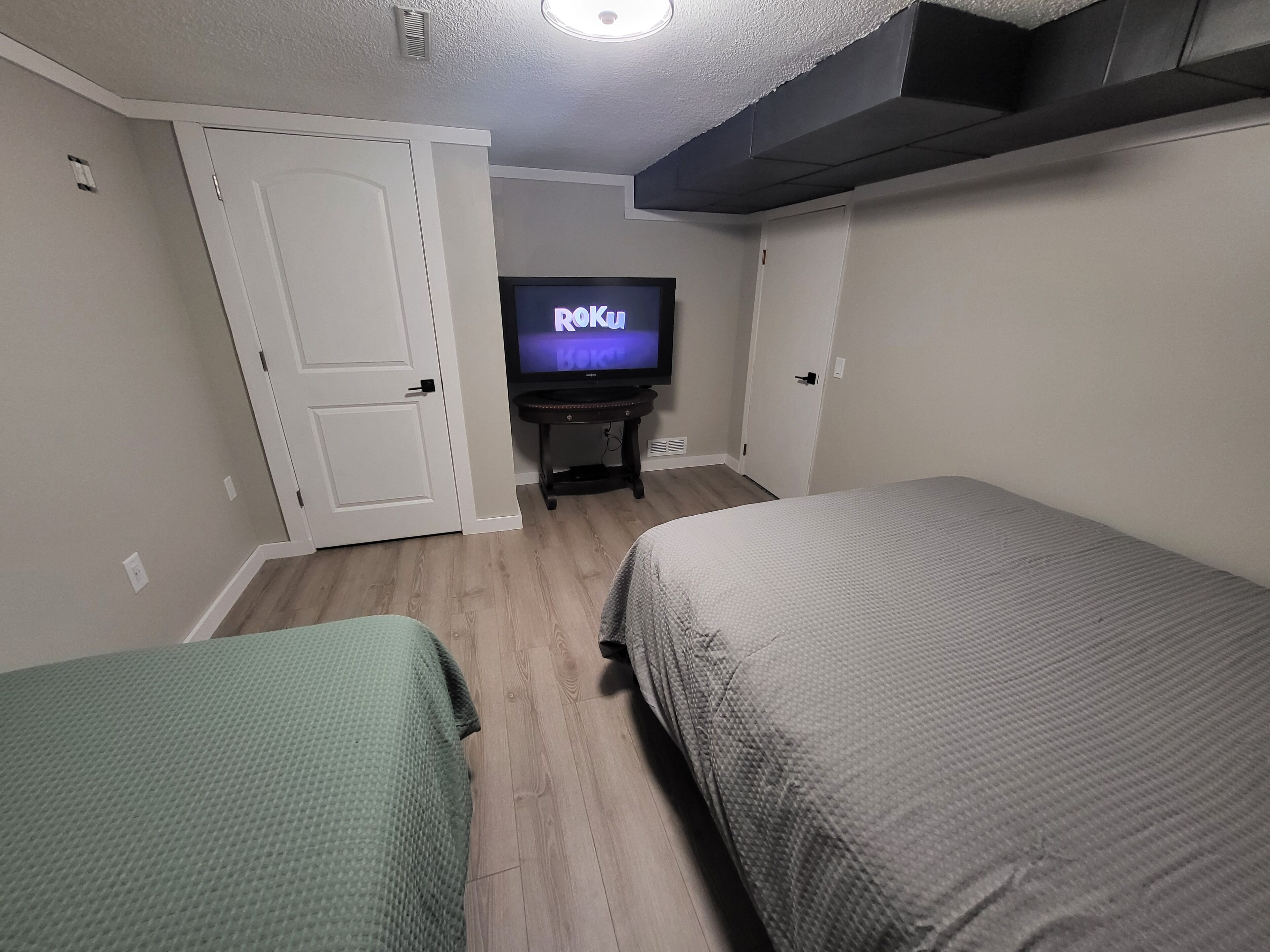 A room with two beds, a television, and a door.