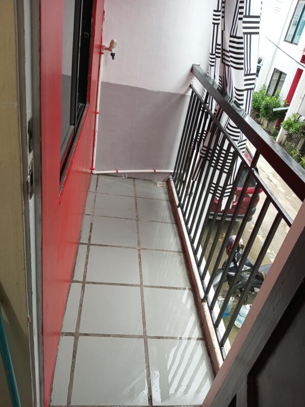 A narrow balcony with tiled flooring, a metal railing, and a view of a building with striped awnings. - Deca Homes - Hernan Cortes (Cebu City)