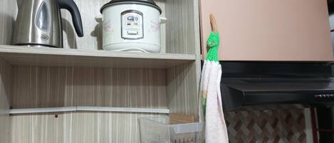 A kitchen with a kettle, a rice cooker, and a hanging towel.