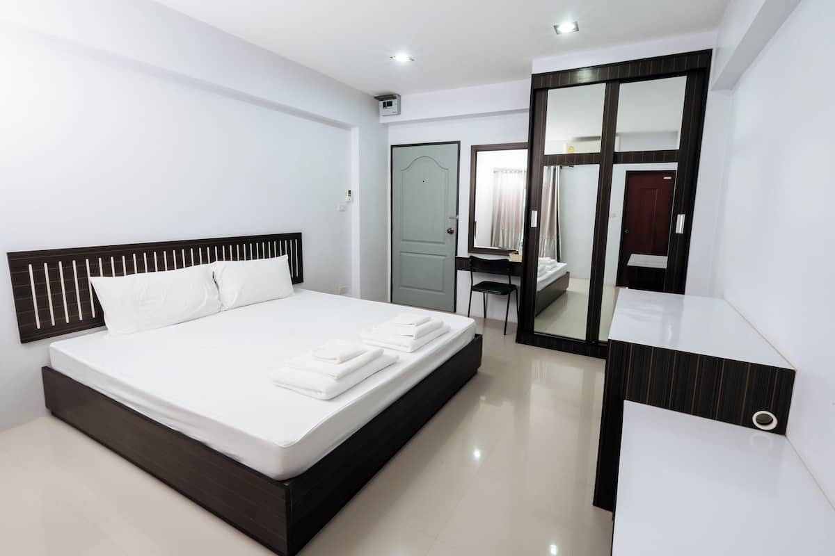 A modern bedroom with a large bed, a desk, and a mirror.