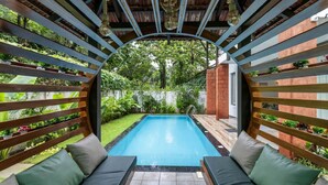 Un espace piscine agrémenté d’une pergola en bois, de coins salon et d’une végétation luxuriante.