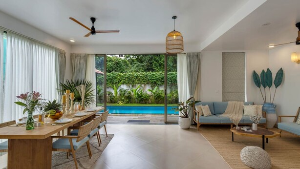 Un salon moderne avec un coin repas, une piscine et une vue sur une végétation luxuriante.