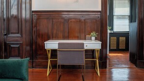 A room with a wooden paneled wall, a desk with a chair, a wall-mounted light fixture, and a door with a window. - Luxurious Loft Suite at Mansfield, Central NYC Location near Top Attraction (New York)