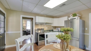 A kitchen with white cabinets, a stainless steel refrigerator, and a dining table with placemats and vases.