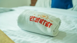 Un asciugamano piegato con ricamo sul letto.