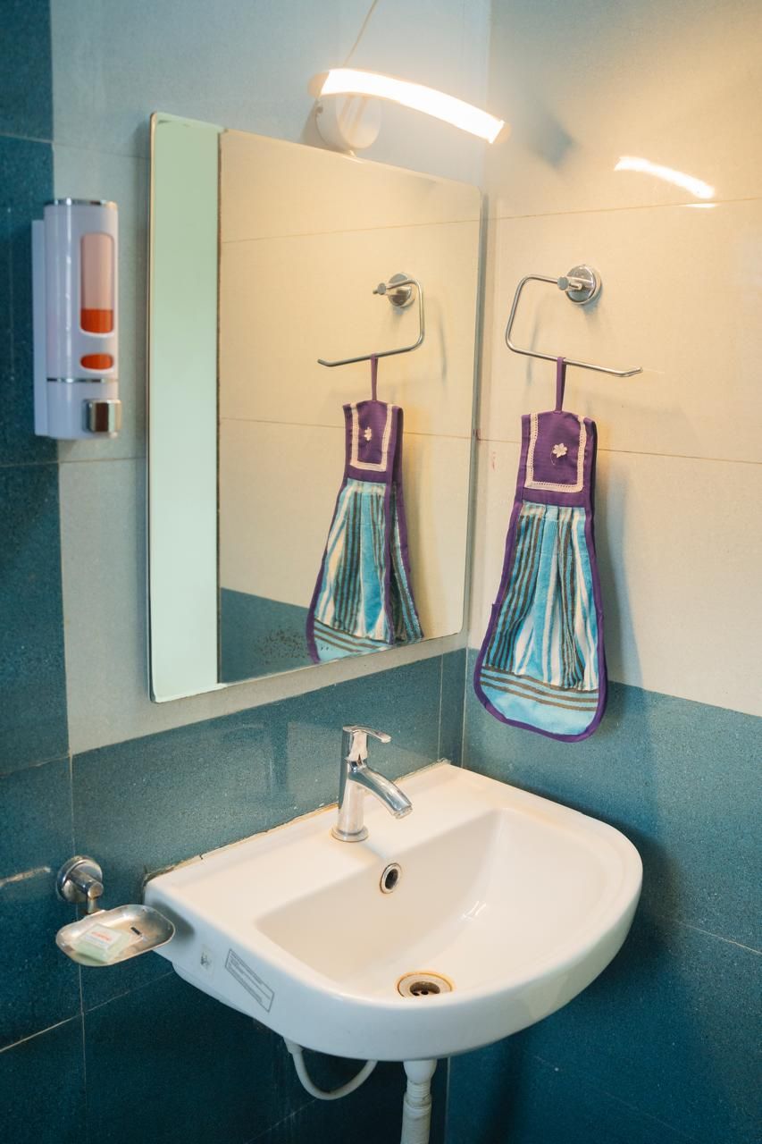 A bathroom with a white sink, a mirror, and a towel rack with a towel.