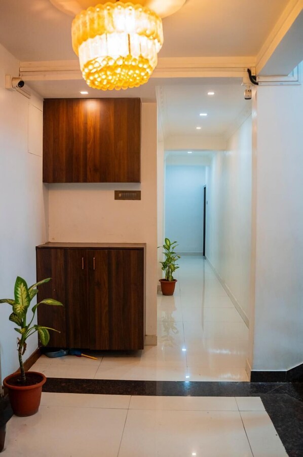 A modern hallway with a wooden cabinet, a potted plant, and a chandelier.