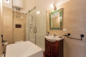 Une salle de bain avec une douche à parois de verre, un lavabo blanc et un meuble-lavabo en bois.
