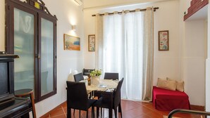 A dining area with a table set for four, a piano, and a red bed in the corner. - Le dimore del mito - Atalanta (Syracuse)