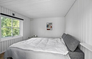 Ein Schlafzimmer mit einem Bett, einem Fenster und einer an der Wand befestigten Bücherablage.