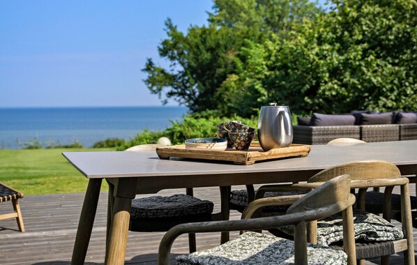 Una terraza de madera con una mesa preparada para el té, con vistas a un cuerpo de agua.