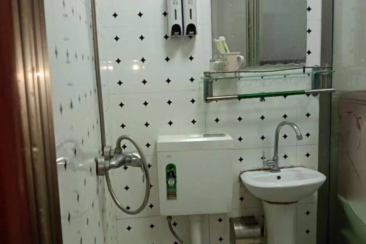Un baño con inodoro, lavamanos y estante de vidrio con artículos de aseo.