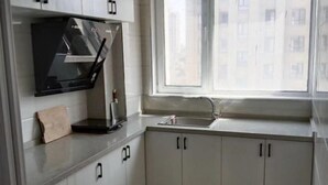 Una cocina con armarios blancos, un microondas negro, una ventana y un fregadero.