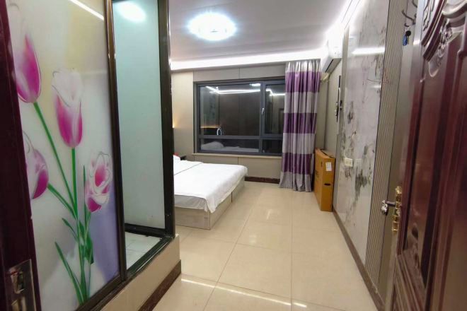 Una habitación de hotel con cama, ventana, cortina y puerta.