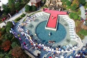 Une piscine circulaire dotée d’une terrasse rouge, entourée d’un sentier en pierre et de bancs.