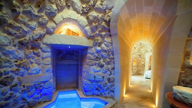 Ein Spa-Bereich mit Steinwänden, einer Whirlwanne und einer hölzernen Sitzbank.