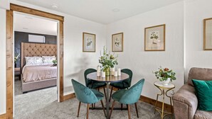 A room with a bed, a round table with chairs, a small side table, and framed pictures on the wall. - Premier Montana Retreat | River + Mountain Views | W & R (Great Falls)