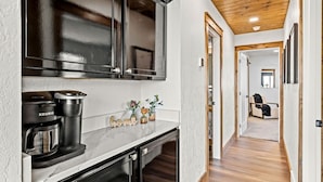 A modern kitchen with black cabinets, a coffee maker, and decorative items on the counter. - Premier Montana Retreat | River + Mountain Views | W & R (Great Falls)