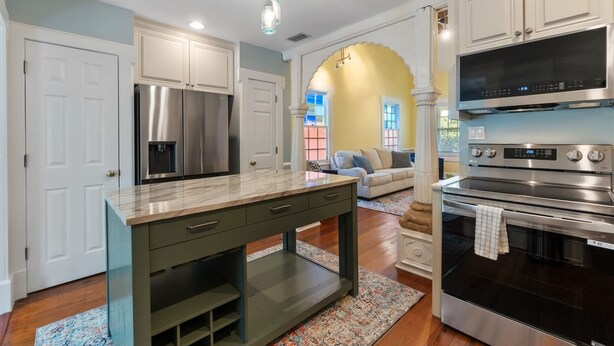 A modern kitchen with stainless steel appliances, a marble countertop, and a central island. - Casa Amarillo l Steps to Historic District (St. Augustine)